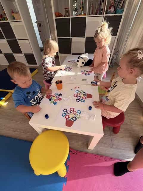 Deti spoločne tvoria pri stole počas tvorivo-rozvojovej dielničky